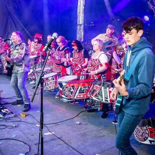Drummers on a stage with a man on guitar