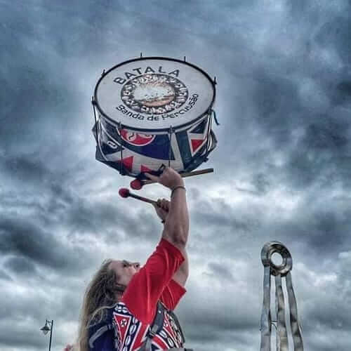 Man lifts drum in the air against cloudy sky